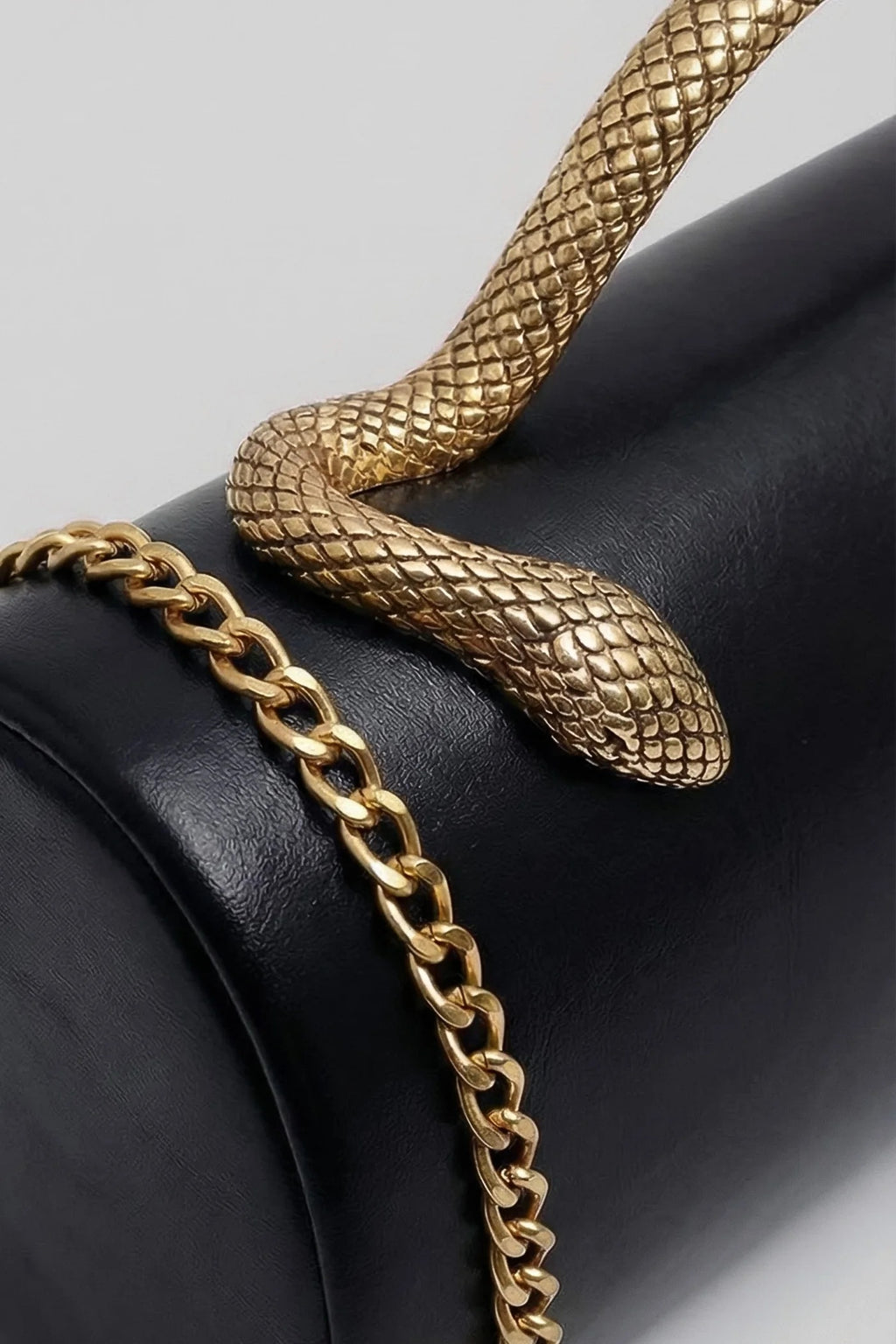 BOLSO DE MANO ESTRUCTURADO CON ASA DE SERPIENTE Y CADENA DORADA - NEGRO